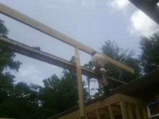 Carpenter setting a ridge beam over a new addition frame — Ice Dam Removal by Roofing Brothers in Arverne