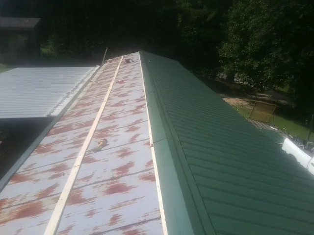 Old rusted panels beside newly installed green metal roofing — Wind Damage Roof Repair by Roofing Brothers in Arverne