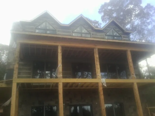 Dormers and porch framing on a large log home under construction — Roof Coating work by our crew in Arverne