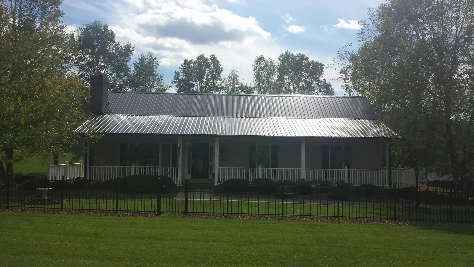 Gray metal roof on a brick ranch with a full width front porch — Gutter Guard Installation work by our crew in Arverne