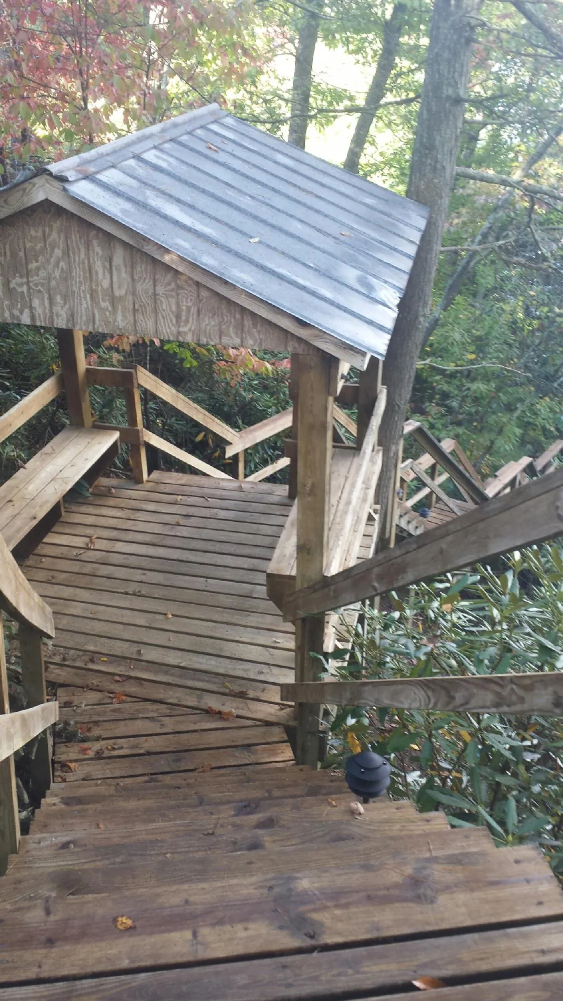 Metal roofed shelter over wooden steps on a wooded walkway — Skylight Repair & Installation work by our crew in Arverne