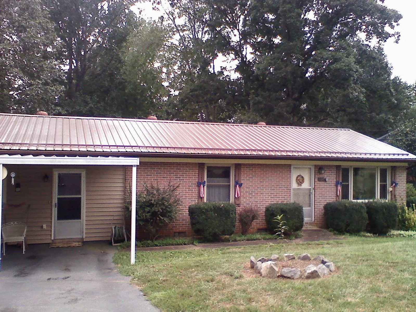 Bronze metal roof and carport on a brick ranch home — Roof Repair work by our crew in Arverne