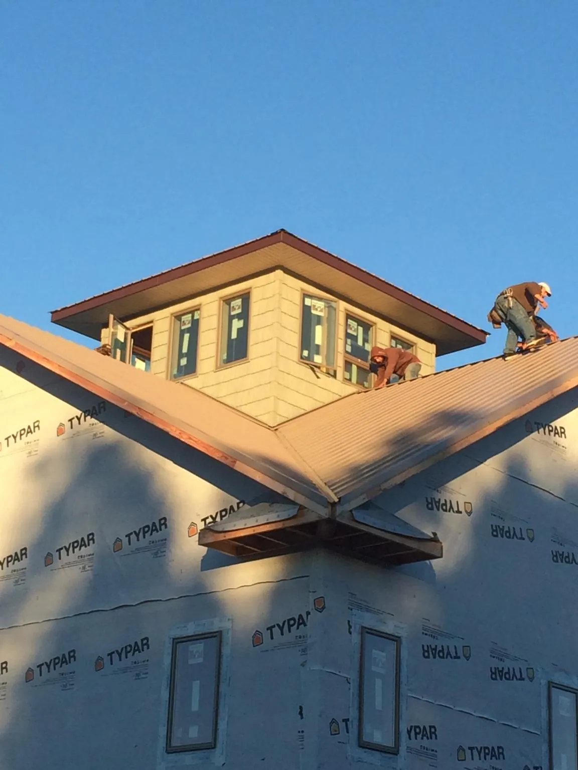 Roofers working around a rooftop cupola on a new metal roof at sunset — Roof Waterproofing in Arverne by Roofing Brothers